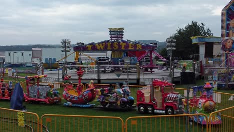 Empty-overcast-British-amusement-park-aerial-view-deserted-funfair-rides-low-dolly-left