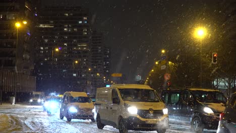 Winter-Scenery-of-Cars-on-Snowy-Street-in-Illuminated-City-at-Night