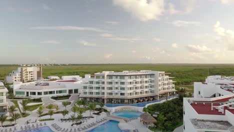 AERIAL---Hotel,-swimming-pool-and-the-horizon-in-Cancun,-Mexico,-spinning-shot