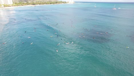 Rotating-4k-aerial-drone-shot-of-surfers-lining-up-at-a-popular-surfing-spot-on-a-tropical-island