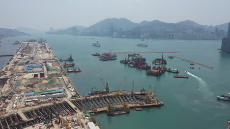 Kowloon-Bay,-Hongkong,-China,-Luftaufnahme-Des-Kreuzfahrtterminals,-Hafenpier-Mit-Gebäuden-Am-Wasser-Im-Nebligen-Hintergrund,-Drohnenaufnahme