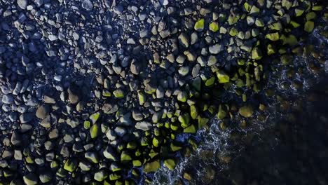 Waves-Splashing-On-Pebbles-With-Moss-At-The-Shore