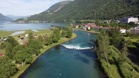 Statische-Antenne-über-Dem-Fluss-Loen-Mit-Touristen,-Die-Auf-Der-Linken-Seite-Campen,-Und-Den-Hotels-Loenfjord-Und-Hotel-Alexandra-Im-Hintergrund---Nordfjord-Norwegen