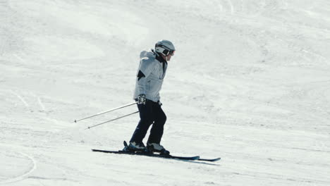 Tracking-shot-of-an-Asian-male-skier-in-white-jacket-skiing-downhill-on-a-cold-winter-day
