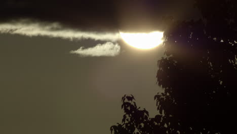 Close-up-static-shot-of-sun-coming-out-from-behind-cloud-during-sunset