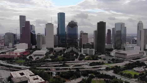 Reverse-drone-shot-of-Houston-skyline-with-cars-driving-on-cloudy-day