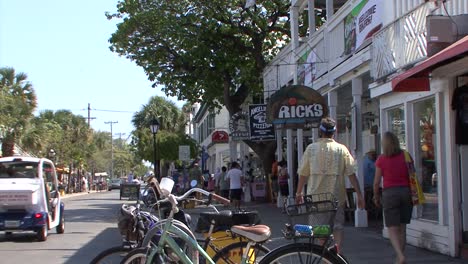People-walk-along-the-bars,-restaurants-and-shops-on-famous-Duval-Street-in-Key-West,-Florida,-USA