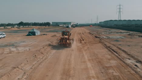 Tractor-Conduciendo-Por-Un-Camino-De-Tierra-En-El-Sitio-De-Construcción-En-Karachi,-Pakistán