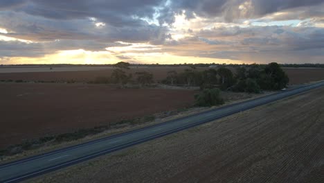 Aerial-side-pan-over-Asphalt-road-on-rural-fields,-Australian-Countryside