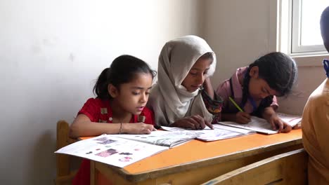 Drei-Junge-Muslimische-Kinder-Lesen-Und-Schreiben-Am-Schreibtisch-Im-Klassenzimmer-In-Pakistan