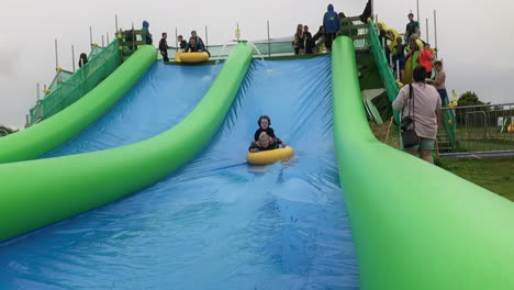 Gente-Divirtiéndose-En-Un-Tobogán-Inflable-Gigante-En-Cornualles,-Reino-Unido