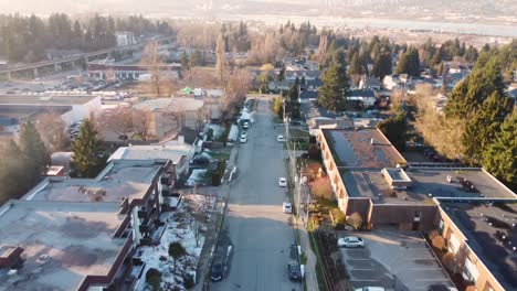 Whalley-neighbourhood-Surrey-BC-Aerial-wide-moving-forward-looking-down-panning-up-to-reveal-condo-buildings-apartments-along-road-leading-to-scenic-view-of-Fraser-River