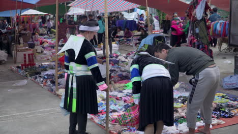 Two-vietnamese-women-buying-flip-flops-at-Ha-Quang-local-market,-Vietnam