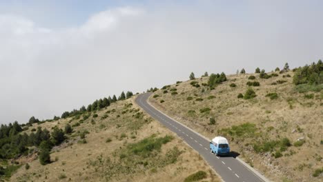 Aerial-is-following-a-VW-Camper-van-on-an-empty-road-on-Madeira-Island,-Portugal