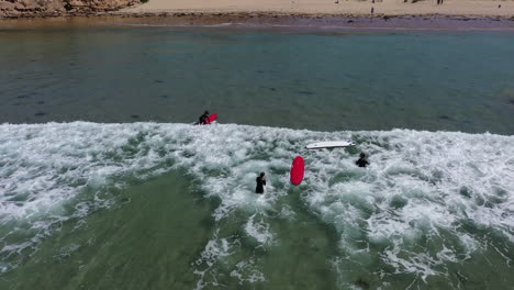 Tracking-aerial-follows-young-surfing-class-as-they-catch-a-small-wave