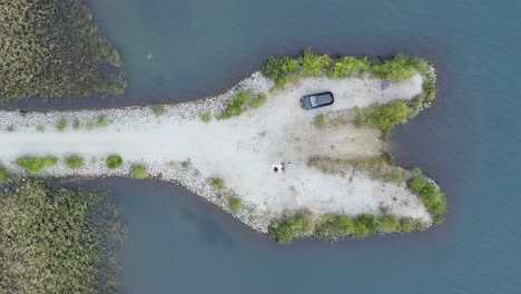A-little-peninsula-with-white-sand-in-a-lake,-filmed-from-above-by-drone
