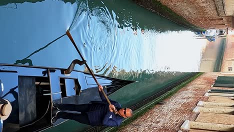 High-angle-view-of-Gondola-with-tourist-woman-and-gondolier-rowing-in-city-canal,-Venice-in-Italy
