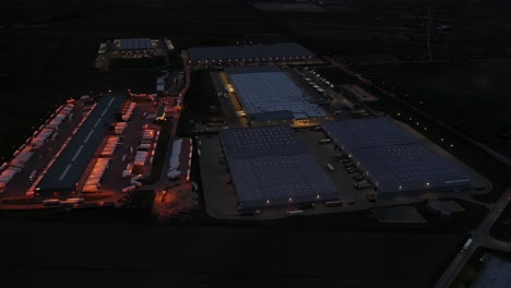 Aerial-view-of-the-large-logistics-park-with-warehouse,-loading-hub-with-many-semi-trailers-trucks-standing-at-the-ramps-for-load-unload-goods-at-night