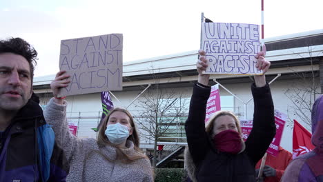 Two-women-hold-up-handmade-cardboard-placards-that-read,-“Stand-Against-Racism”-and-“Unite-Against-Racism”-during-a-protest-against-far-right-spokesperson-Tommy-Robinson-