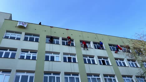 Charity-Climbers-for-WOSP-clean-windows-in-children's-hospital-in-funny-outfit-on-Polanki-Street-in-Gdansk,-Maciej-Płażyński-Hospital