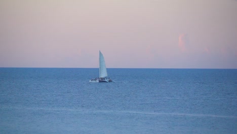 Boat-sailing-across-open-ocean-at-sunset