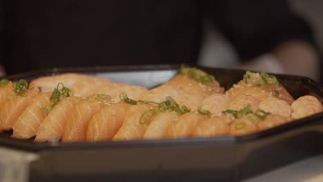 Sushi-En-Caja-Para-Llevar-Con-Chef-Borroso-Trabajando-En-Segundo-Plano