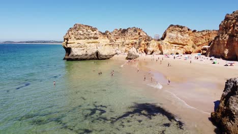 Playa-Praia-Dos-Tres-Irmaos,-Algarve,-Portugal---Vista-Aérea-De-Drones-De-La-Costa-Con-Playas,-Turistas,-Acantilados-Rocosos-Y-Hoteles