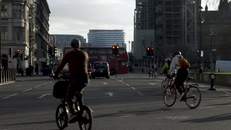 The-early-morning-hustle-as-people-make-their-way-into-the-city-of-London-by-bicycle-and-other-modes-of-transport,-the-commuters-turning-off-Parliament-square-down-Great-George-Street,-Westminster,-UK