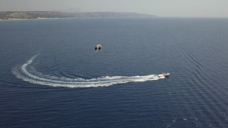 Tourists-enjoy-colorful-parasail-ride-behind-tour-boat-in-blue-water