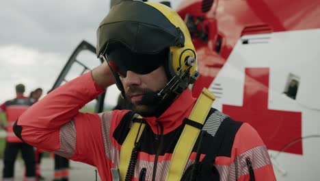 Closeup-shot-of-Rescuer-adjusting-his-helmet-in-front-of-Helicopter---slowmotion