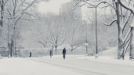 Man-Rides-Bicycle-On-Snow-Covered-Road-In-Central-Park,-New-York-City