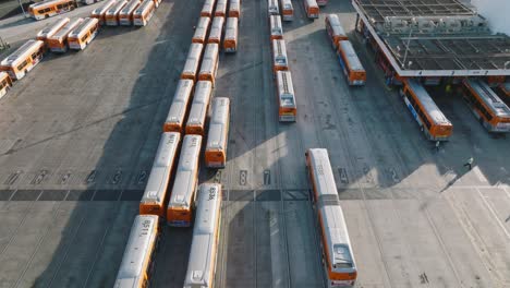 LA-Metro-Buses-Parked-at-Station,-Aerial-Drone-Shot-Flying-Over-Orange-Buses