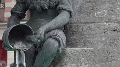 A-closeup-of-one-of-the-bronze-butcher-boys,-pouring-water-into-the-basin-from-a-bucket
