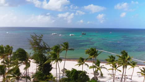 Palmen-Im-Wind,-Sandstrand-Und-Boote-Am-Karibischen-Meer-Im-Hintergrund,-Drohnenaufnahme-Der-Dominikanischen-Republik,-Punta-Cana-Bavaro-Resort