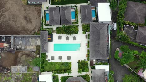 Luftaufnahme-Von-Oben-Nach-Unten-Eines-Wunderschönen-Poolvilla-Hotels-Neben-Einer-Baustelle-In-Bali,-Indonesien