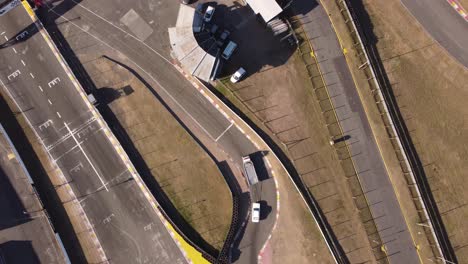 Aerial-top-down-shot-of-trucking-towing-away-race-car-after-accident-on-racetrack