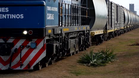 Slow-motion,-close-shot-of-a-freight-train-passing-through-a-country-town