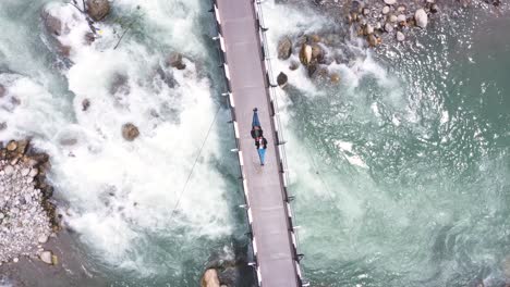 Luftdrohnen-Vogelperspektive-über-Ein-Paar,-Das-Auf-Dem-Weg-Nach-Manali,-Himachal-Pradesh,-Indien,-über-Einer-Hängebrücke-über-Einen-Fluss-Liegt