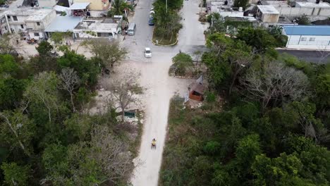 An-aerial-view-of-dirt-road-in-Akumal-where-bike-riding-is-seen-along-while-one-car-is-passing-by