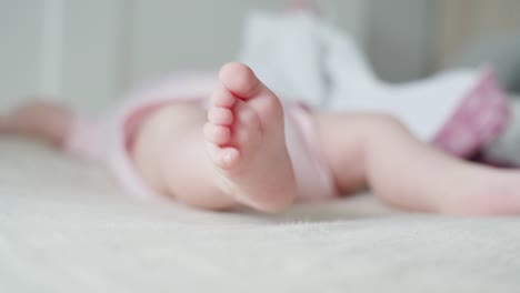 Baby-Liegt-Auf-Dem-Bett,-Krümmt-Die-Zehen,-Während-Es-Die-Füße-Bewegt,-Selektiver-Fokus