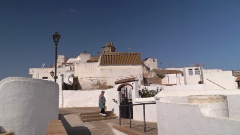 Anciano-Entrando-A-Casa-En-Un-Típico-Pueblo-Encalado-En-El-Sur-De-Europa