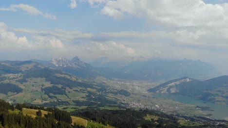 Panorama-of-alpine-valley-and-Mythen-mountains-from-Wildspitz-peak,-Switzerland,-aerial-drone-view