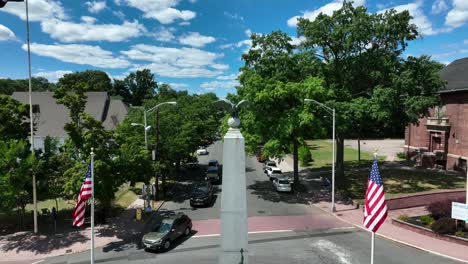 Small-town-square-with-American-flags,-eagle-and-statue