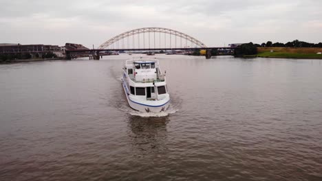 Aerial-Circle-Dolly-Around-Forward-Bow-Of-Smaragd1-Party-ship-Going-Past-On-River-Noord