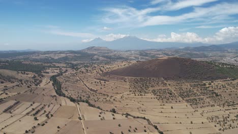 Aerial-view-of-the-cropland-in-the-Mexican-state-of-Tlaxcala,-with-the-Iztaccihuatl-and-Popocatepetl-volcanoes-or-mountains-in-the-background