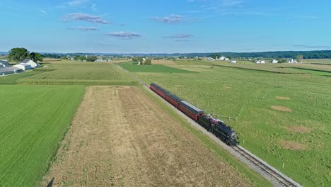 A-Drone-View-of-an-Antique-Steam-Passenger-Train-Blowing-Smoke-and-Steam-Traveling-Thru-Fertile-Corn-Fields-on-a-Beautiful-Late-Afternoon-Sunny-Summer-Day