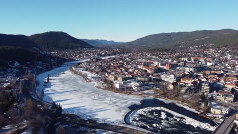 Numedalslagen-river-during-sunny-winter-morning---Backward-moving-panoramic-aerial-view-from-Kongsberg-city-centre