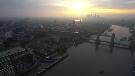 Cinematic-Aerial-View-of-London,-England-UK-at-Sunset,-Tower-Bridge,-Thames-River-and-Misty-Cityscape-Skyline
