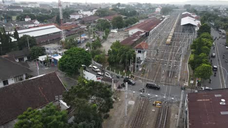 Vista-Aérea,-Tráfico-Pesado-Que-Pasa-Por-El-Cruce-Ferroviario-Adyacente-A-La-Estación-Lempuyangan-De-Yogyakarta
