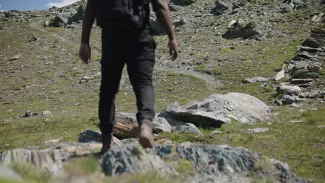 Black-male-traveler-with-backpack-walking-across-screen-to-explore-the-Matterhorn-mountainside-in-Switzerland